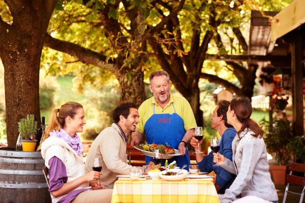 Tschebull Senior serviert Gericht für Gäste im Garten.