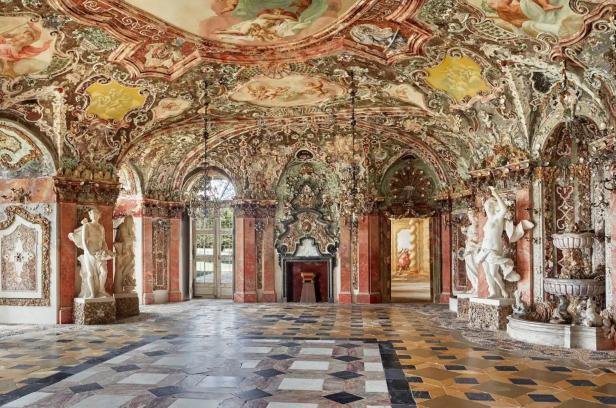 Ein prunkvoller Saal mit Marmorboden, Statuen und reich verzierter Decke.