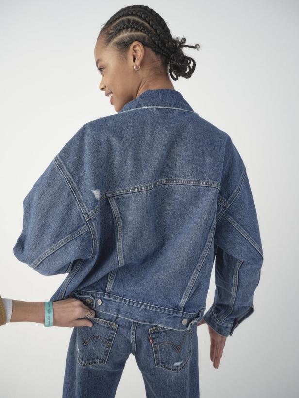 Eine Frau mit Zöpfen trägt eine Jeansjacke und Jeans von Levi's.