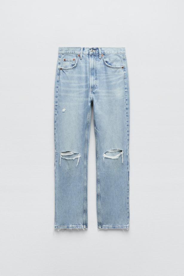 Eine hellblaue Jeans mit Rissen an den Knien liegt vor einem weißen Hintergrund.