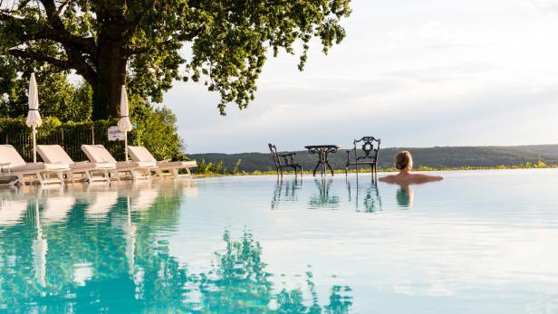Eine Frau entspannt in einem Infinity-Pool mit Blick auf die Landschaft.