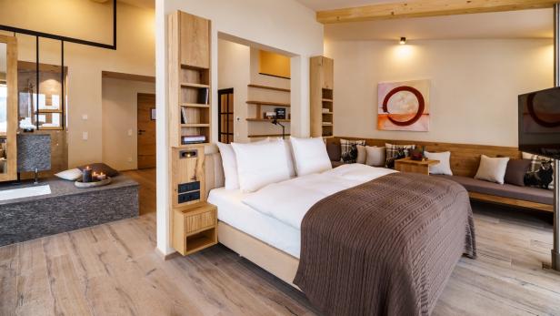 Ein modernes Schlafzimmer mit Holzboden, einem Doppelbett und einem angrenzenden Badezimmer.