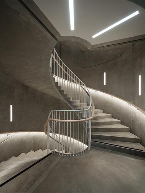 Eine Wendeltreppe aus Beton mit einem weißen Geländer in einem Gebäude in Uppsala.