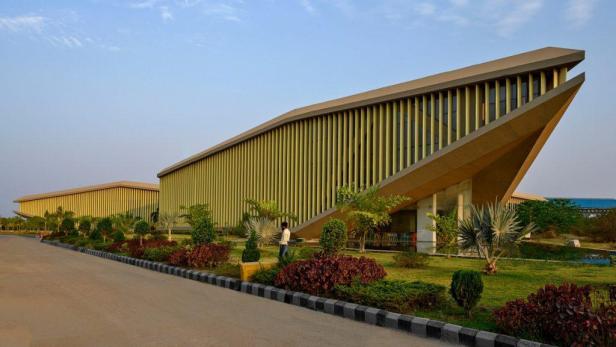 Ein modernes Gebäude mit vertikalen Lamellen und einem Mann im Garten.