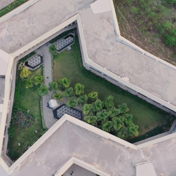 Luftaufnahme eines begrünten Innenhofs zwischen Gebäuden in Indien.