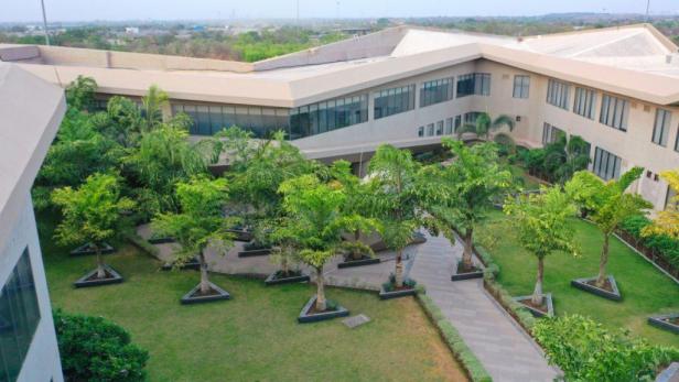 Ein modernes Gebäude mit einem begrünten Innenhof mit Bäumen und Rasenflächen.