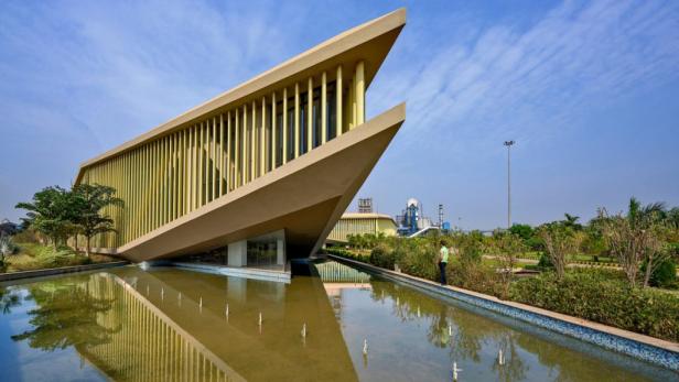 Das moderne Verwaltungsgebäude eines Stahlwerks in Indien spiegelt sich im Wasser.