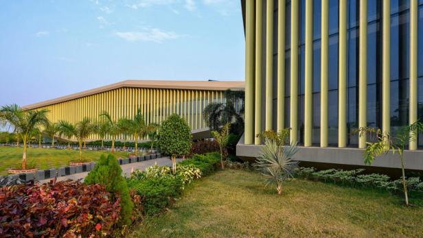 Ein modernes Gebäude mit vertikalen Säulen und üppiger Landschaftsgestaltung.