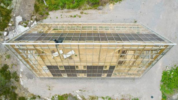 Luftaufnahme eines modernen Holzhauses mit Solarpaneelen auf dem Dach.