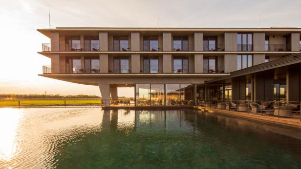Ein modernes Hotelgebäude mit Pool im goldenen Abendlicht.