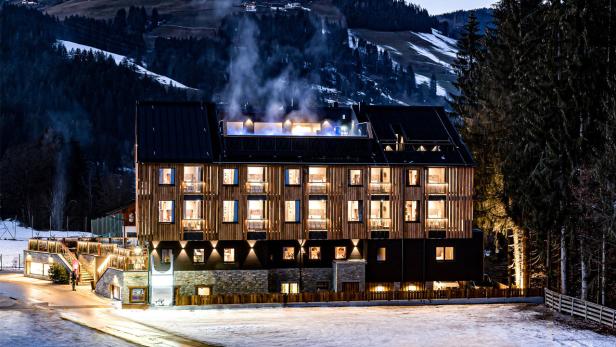 Ein modernes Hotel mit beleuchteten Fenstern in einer verschneiten Winterlandschaft.
