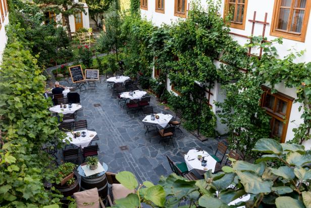 Gastgarten in einem Innenhof mit viel Grün.