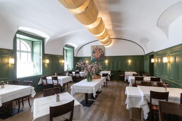 Ein Speisesaal mit weiß gedeckten Tischen und grünen Wandpaneelen.