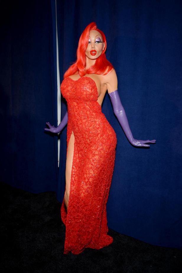 Eine Frau, verkleidet als Jessica Rabbit, in einem roten, glitzernden Kleid und lila Handschuhen.