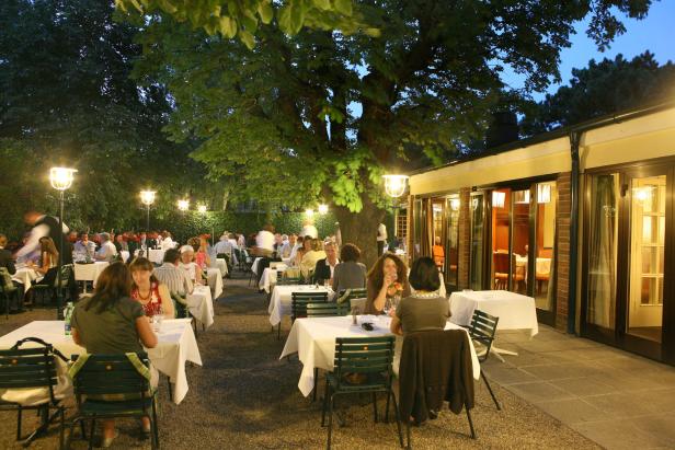 Gäste sitzen im Freien im Restaurant Eckel an Tischen mit weißen Tischdecken.