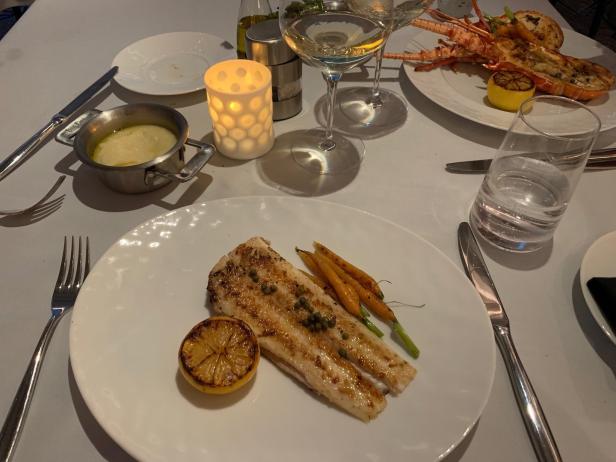 Ein gedeckter Tisch mit Fisch, Hummer, Karotten und Zitrone.