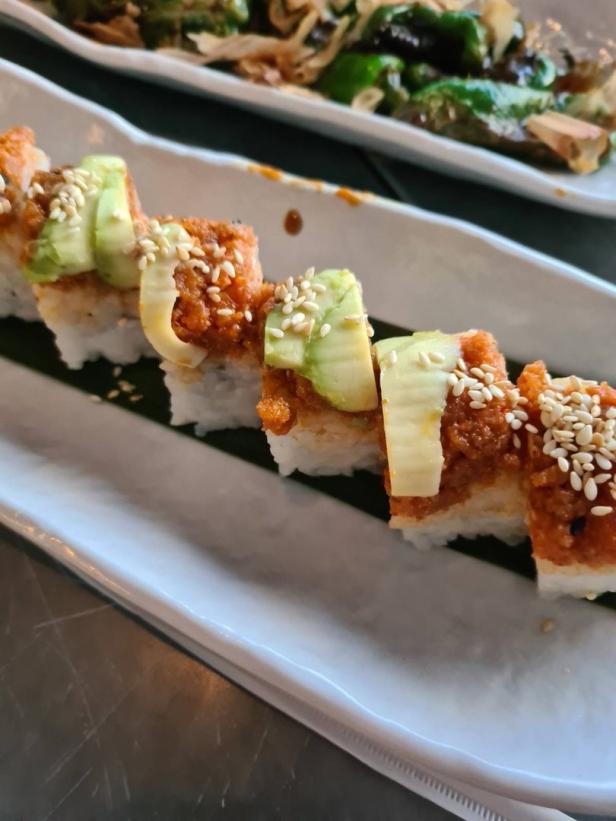 Eine Platte mit Sushi, garniert mit Avocado und Sesamkörnern.