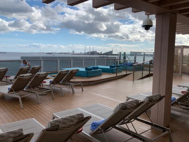 Ein sonniger Tag auf dem Deck eines Kreuzfahrtschiffes mit Liegestühlen und Meerblick.