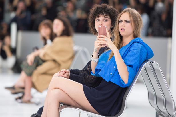 Cara Delevingne sitzt mit einer Freundin zusammen und schaut überrascht.