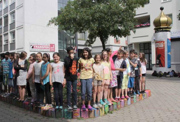 Eine Gruppe von Schulkindern steht im Freien vor einem Gebäude.