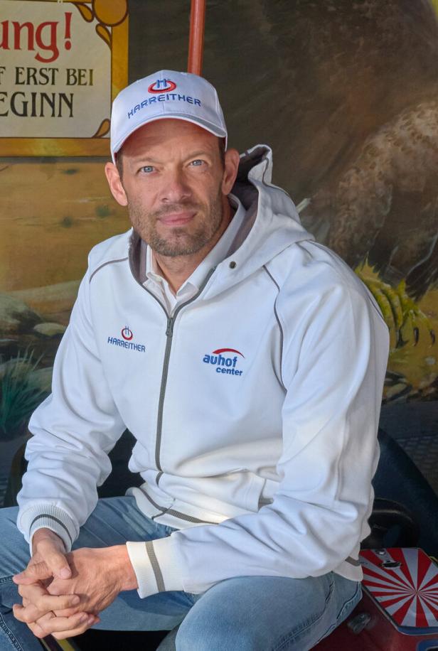 Alexander Wurz sitzt in Freizeitkleidung auf einem Karussell.