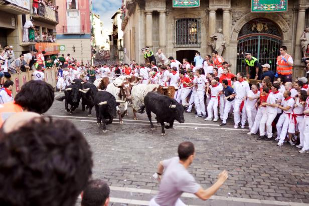 Beim San Fermín Fest rennen Menschen vor Stieren durch die Straßen von Pamplona.
