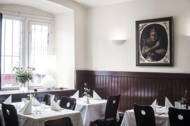 Ein Speisesaal im Restaurant Oswald & Kalb mit gedeckten Tischen und einem Gemälde an der Wand.