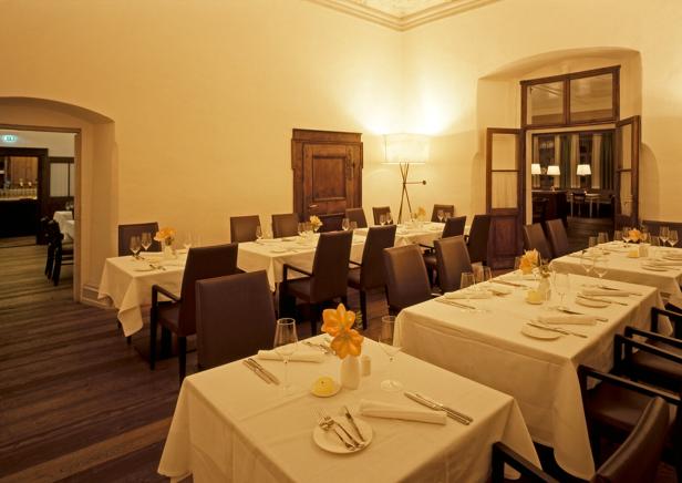 Ein Speisesaal im Pfarrwirt mit gedeckten Tischen und Stühlen.