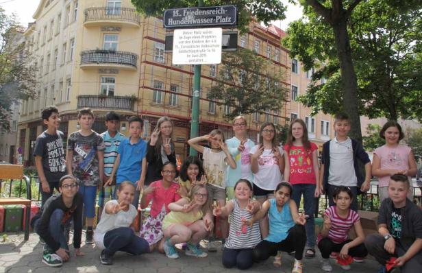 Eine Gruppe von Kindern posiert vor dem „Friedensreich-Hundertwasser-Platz“ in Wien.