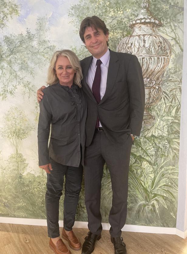 Eine Frau und ein Mann posieren vor einer Wandmalerei.