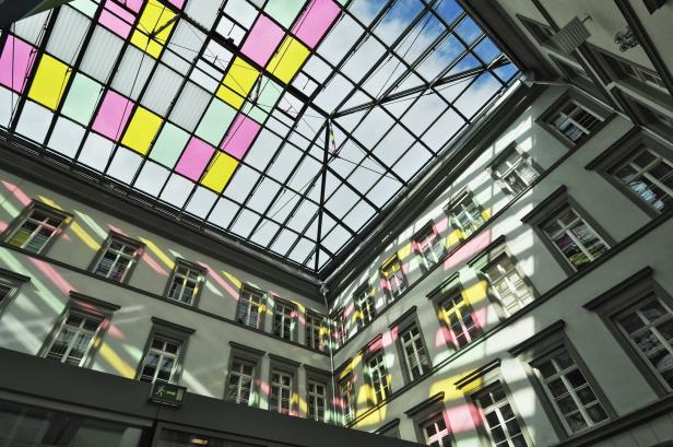 Ein Innenhof mit einem Glasdach, das mit farbigen Feldern verziert ist.