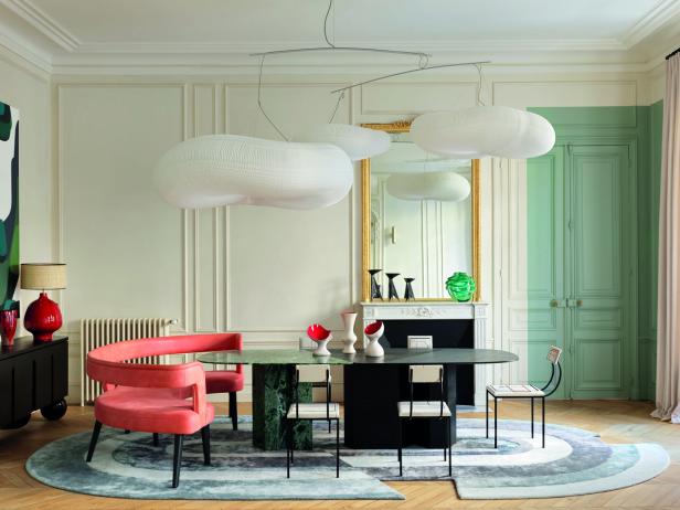 Ein Esszimmer mit einem ovalen Tisch, umgeben von Stühlen und einer skulpturalen Wolkenlampe.