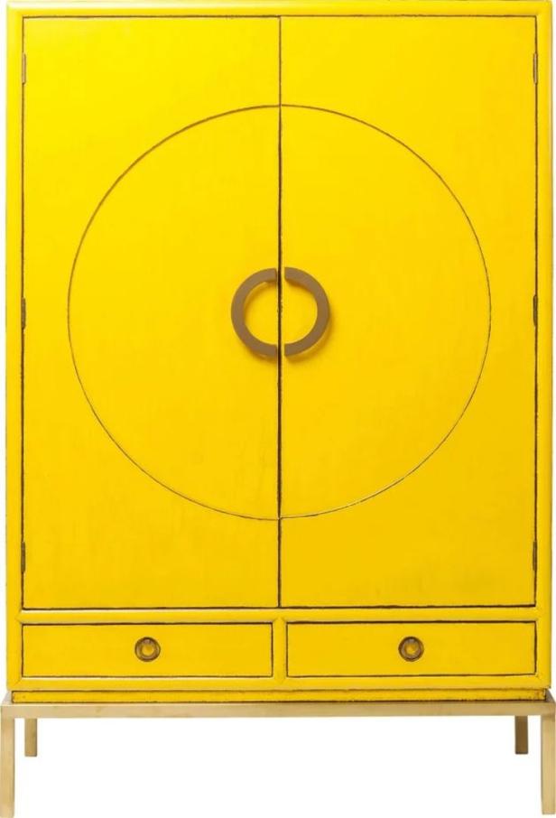 Ein gelber Schrank mit kreisförmigen Griffen und zwei Schubladen steht auf einem goldenen Gestell.
