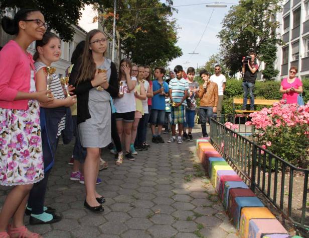 Eine Gruppe Kinder steht mit kleinen goldenen Trophäen in einer Reihe.
