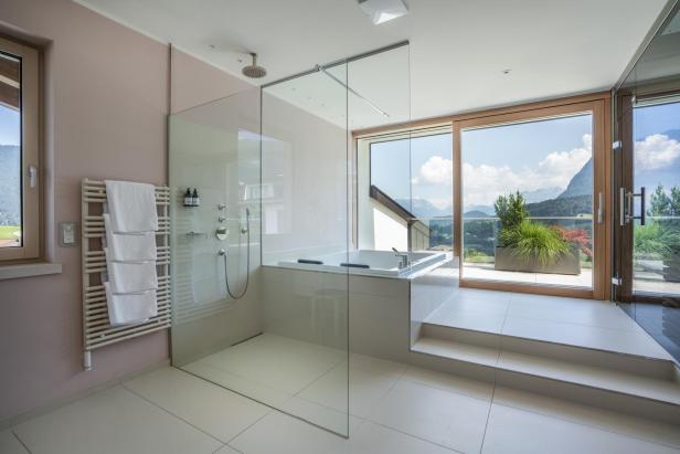 Ein modernes Badezimmer mit Dusche, Badewanne und Blick auf die Berge.