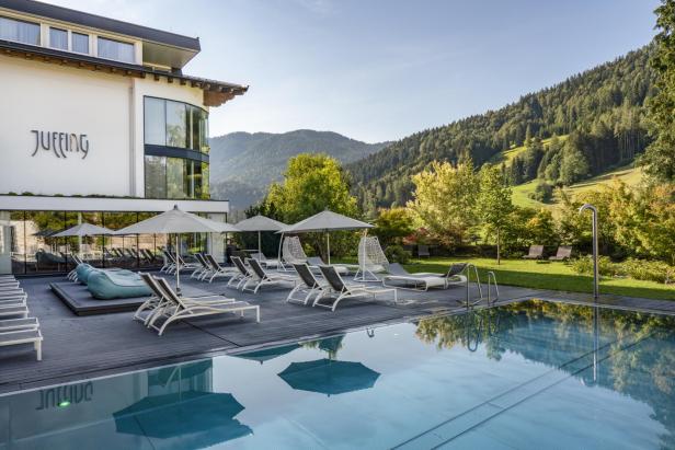 Das Juffing Hotel in den Bergen mit Pool und Liegestühlen.