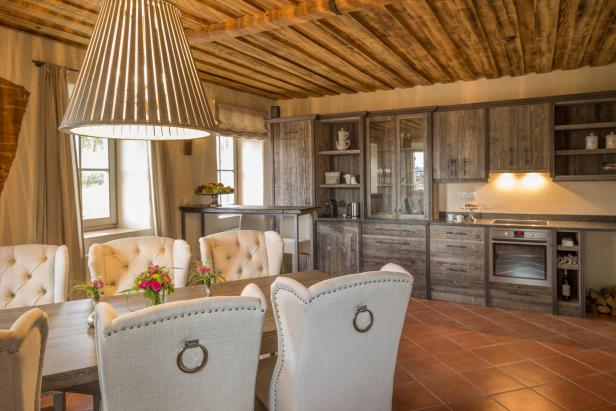 Ein Esszimmer mit Holzbalkendecke und einem Esstisch mit Stühlen.