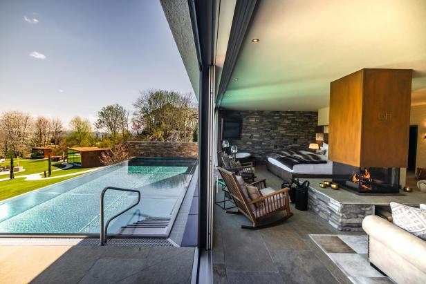 Blick aus einem luxuriösen Hotelzimmer auf einen Infinity-Pool und die Landschaft.