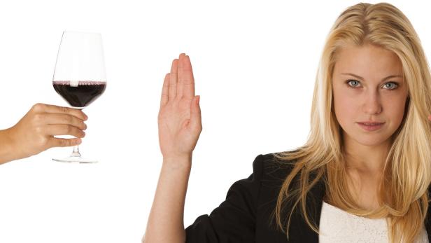 Eine Frau lehnt ein Glas Rotwein ab.