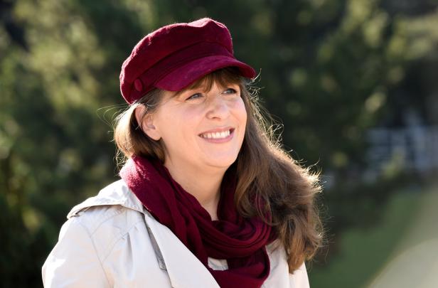 Eine lächelnde Frau mit roter Mütze und Schal blickt nach rechts.