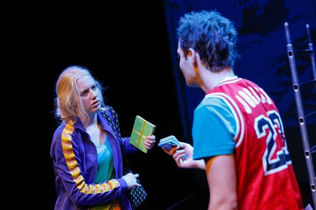 Eine Frau übergibt einem Mann in einem Sporttrikot ein Geschenk und nimmt Geld entgegen.