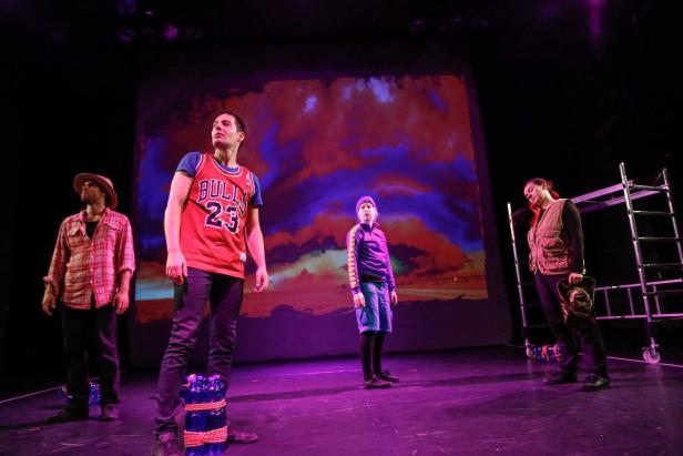 Vier Schauspieler stehen auf einer Bühne vor einer Leinwand mit Himmelsmotiv.