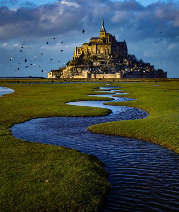 Mont-Saint-Michel, eine französische Inselgemeinde in der Normandie, mit einem Bach im Vordergrund.
