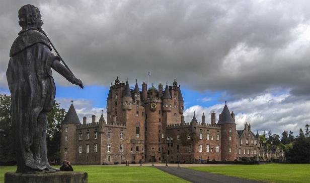 Blick auf Glamis Castle in Schottland mit einer Statue im Vordergrund.