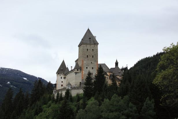 Burg Mauterndorf thront auf einem bewaldeten Hügel.