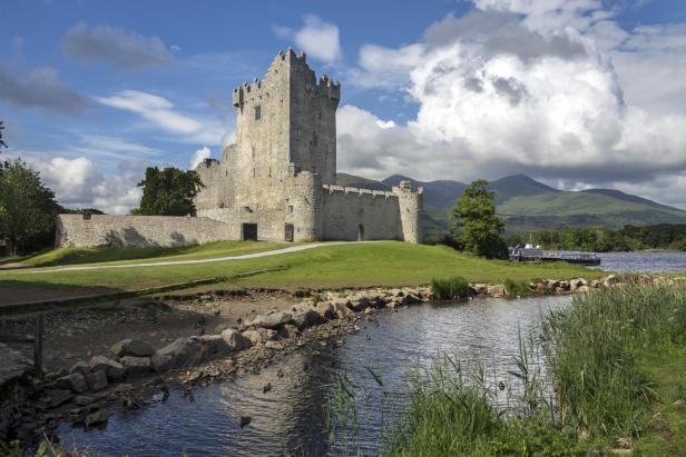 Ross Castle in Irland, umgeben von grüner Landschaft und Wasser.