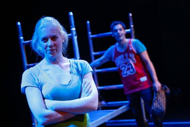 Eine Frau mit verschränkten Armen und ein Mann im Bulls-Trikot auf einer Bühne.