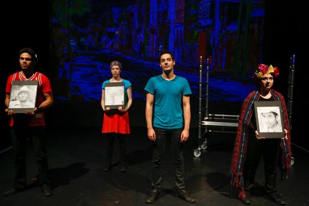 Vier Personen stehen auf einer Bühne und halten gerahmte Porträts in Schwarzweiß.