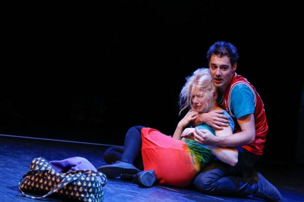 Ein Mann umarmt eine weinende Frau auf einer Bühne.