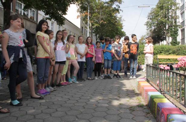 Eine Gruppe von Kindern steht im Freien auf einem gepflasterten Weg.